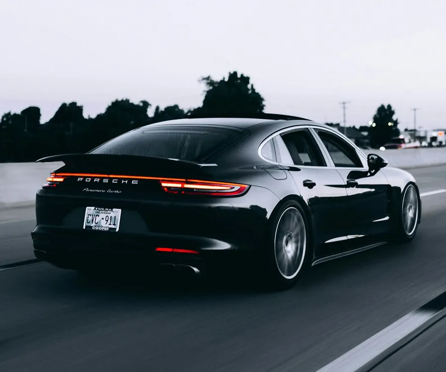 Fotografía de referencia: vista trasera de un Porsche negro en carretera.
